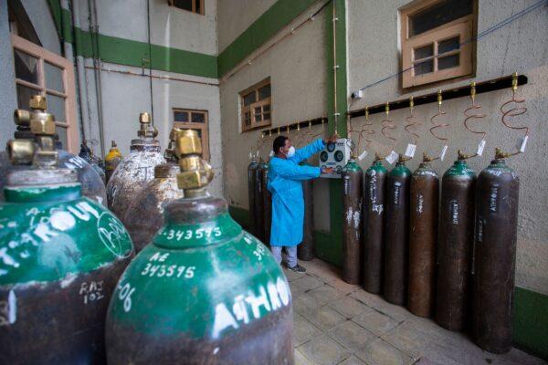 A health worker refills empty oxygen cylinders at a COVID-19 care centre established by District Disaster Management Authorities (DDMA) in Srinagar, India, on May 6, 2021. (Abid Bhat/AFP via Getty Images)