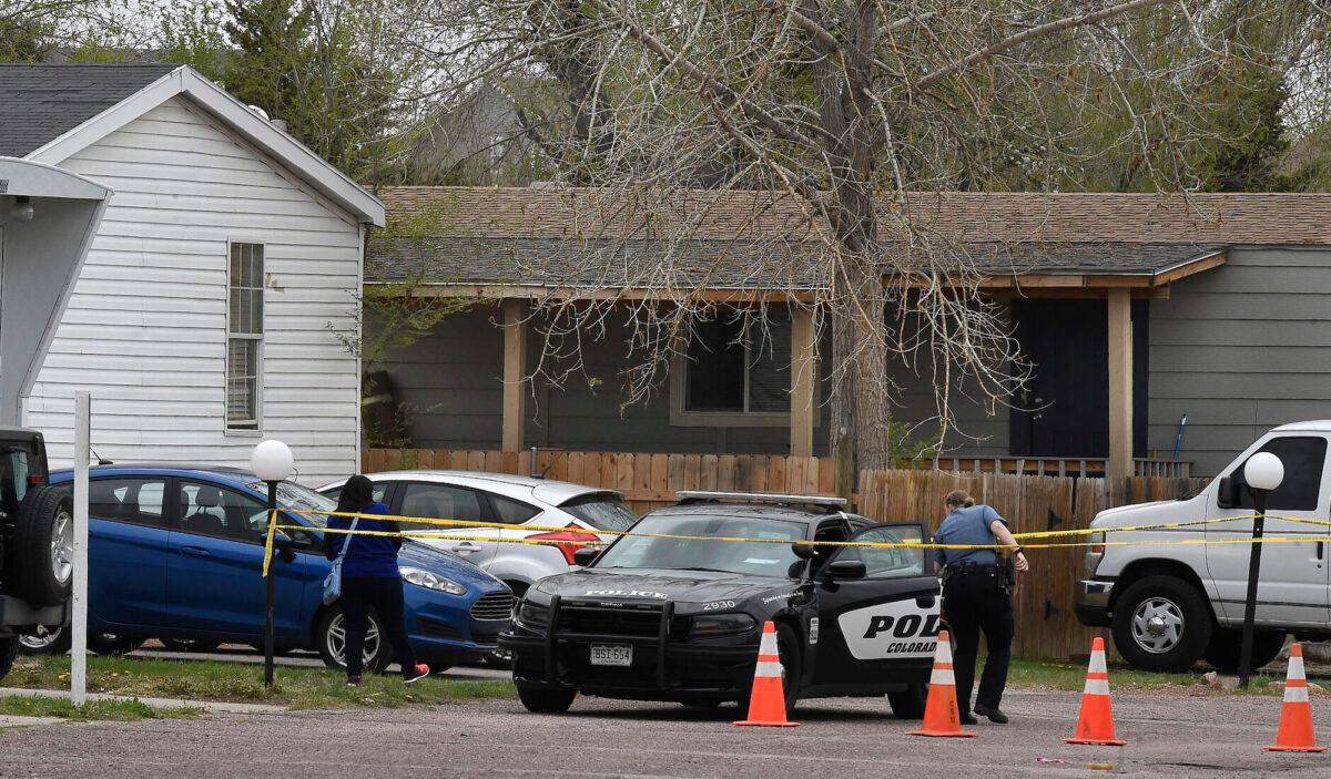 A Colorado Springs police officer goes to help a person get to her car from behind the crime tape in Colorado Springs, Colo., on May 9, 2021. A gunman opened fire at a birthday party, slaying six adults before killing himself. (Jerilee Bennett/The Colorado Springs Gazette via AP)