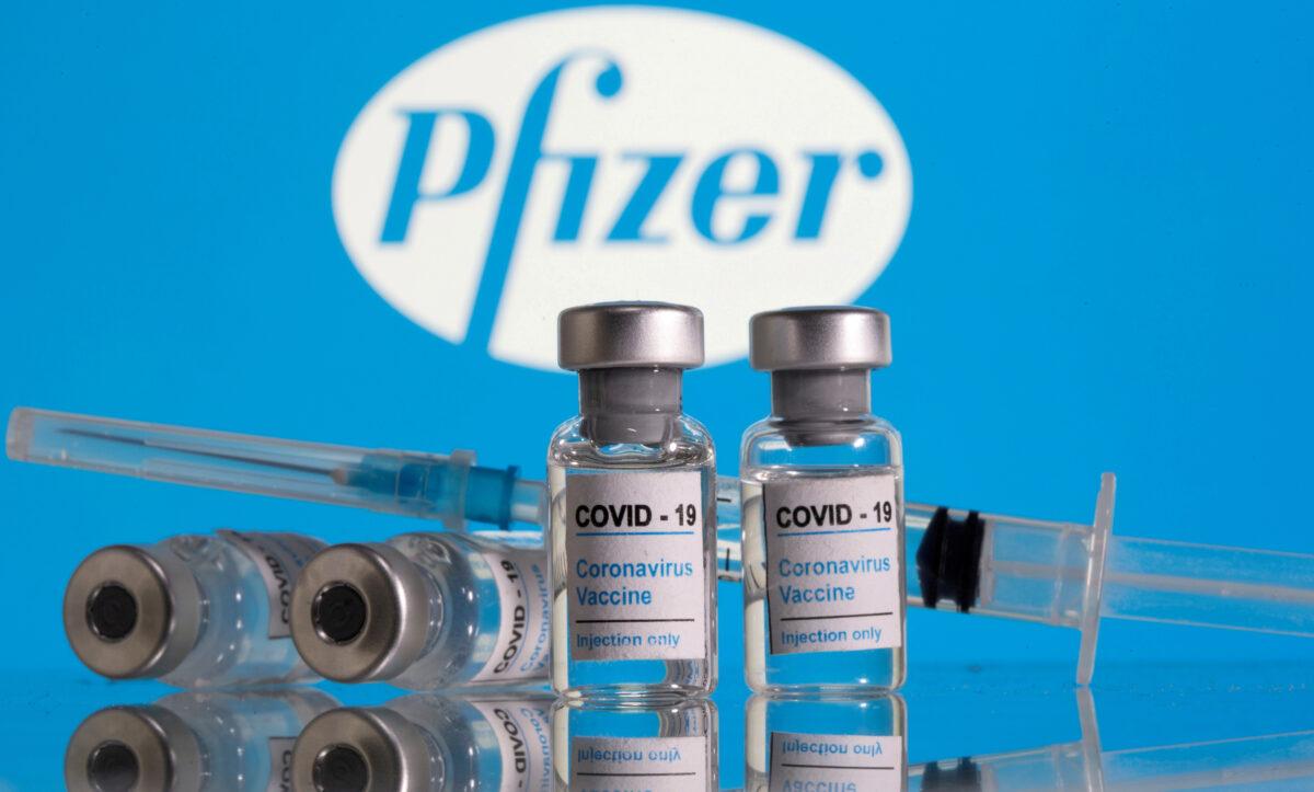 Vials labeled "COVID-19 Coronavirus Vaccine" and a syringe are seen in front of the Pfizer logo in this illustration taken on Feb. 9, 2021. (Dado Ruvic/Reuters)