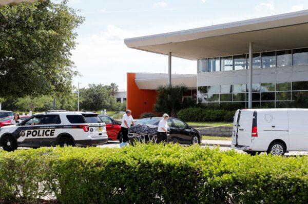 Officials move a body at the site of a fatal shooting outside a U.S. Customs and Immigration Service building in Orlando, Fla., on May 10, 2021. (Joe Skipper/Reuters)