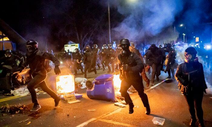 Portland police officers chase demonstrators after a riot was declared in Portland, Ore., on April 12, 2021. (Nathan Howard/Getty Images)