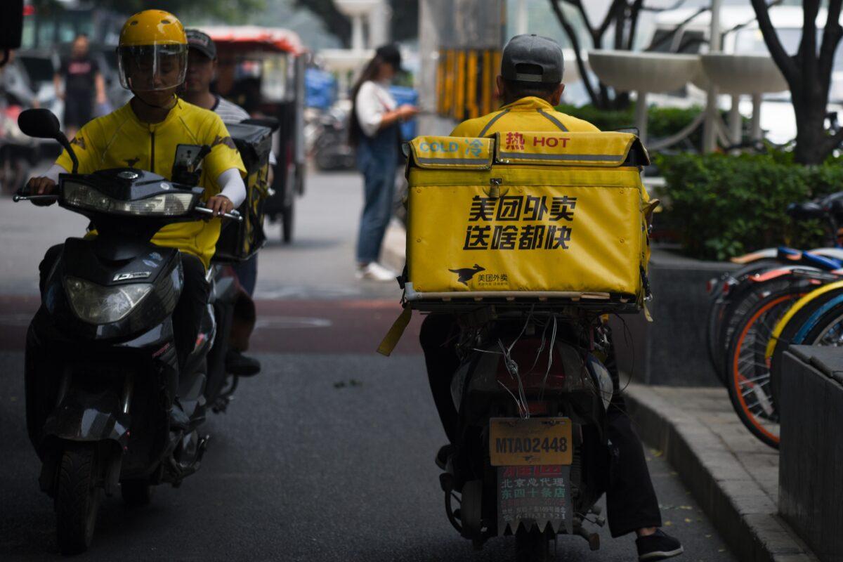 Two Meituan food deliverymen ride their scooters in Beijing on June 26, 2018. (Wang Zhao/AFP via Getty Images)
