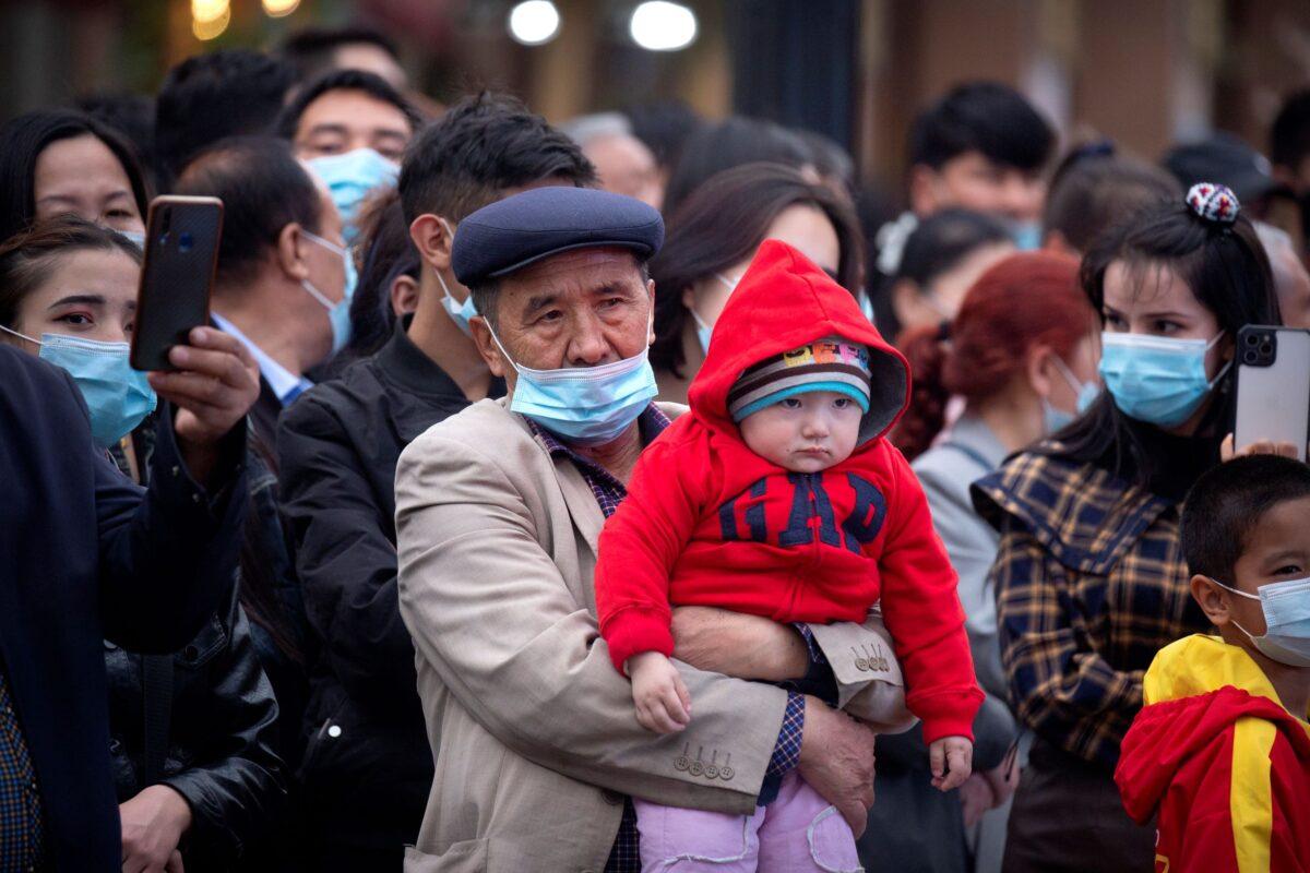 A man holds a child at the International Grand Bazaar in Urumqi, Xinjiang Uyghur Autonomous Region, China, on April 21, 2021. (Mark Schiefelbein/AP Photo)