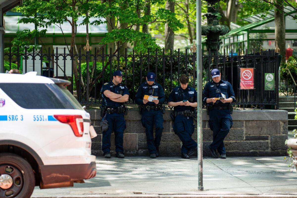 Police officers read about Falun Dafa as a parade by practitioners of the spiritual discipline Falun Gong in New York on May 13, 2020. (Chung I Ho/The Epoch Times)