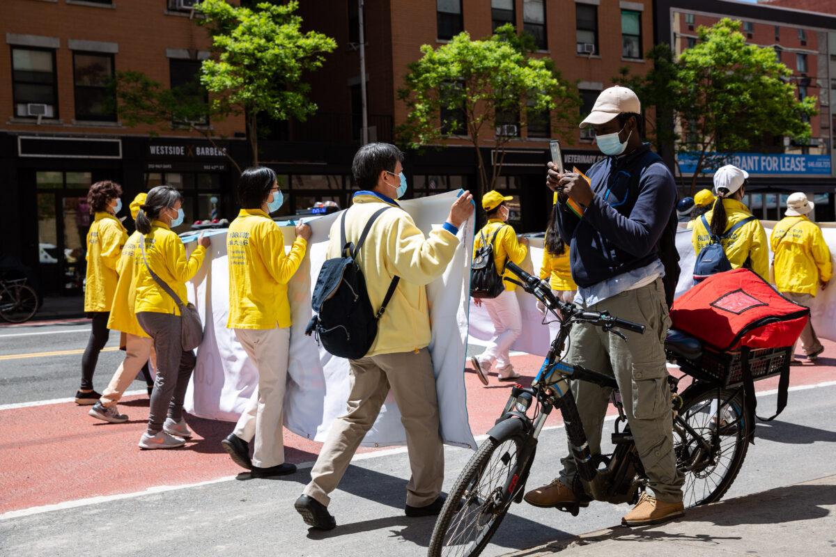 Bystanders watch a parade by practitioners of the spiritual discipline Falun Gong in New York on May 13, 2021. (Chung I Ho/The Epoch Times)