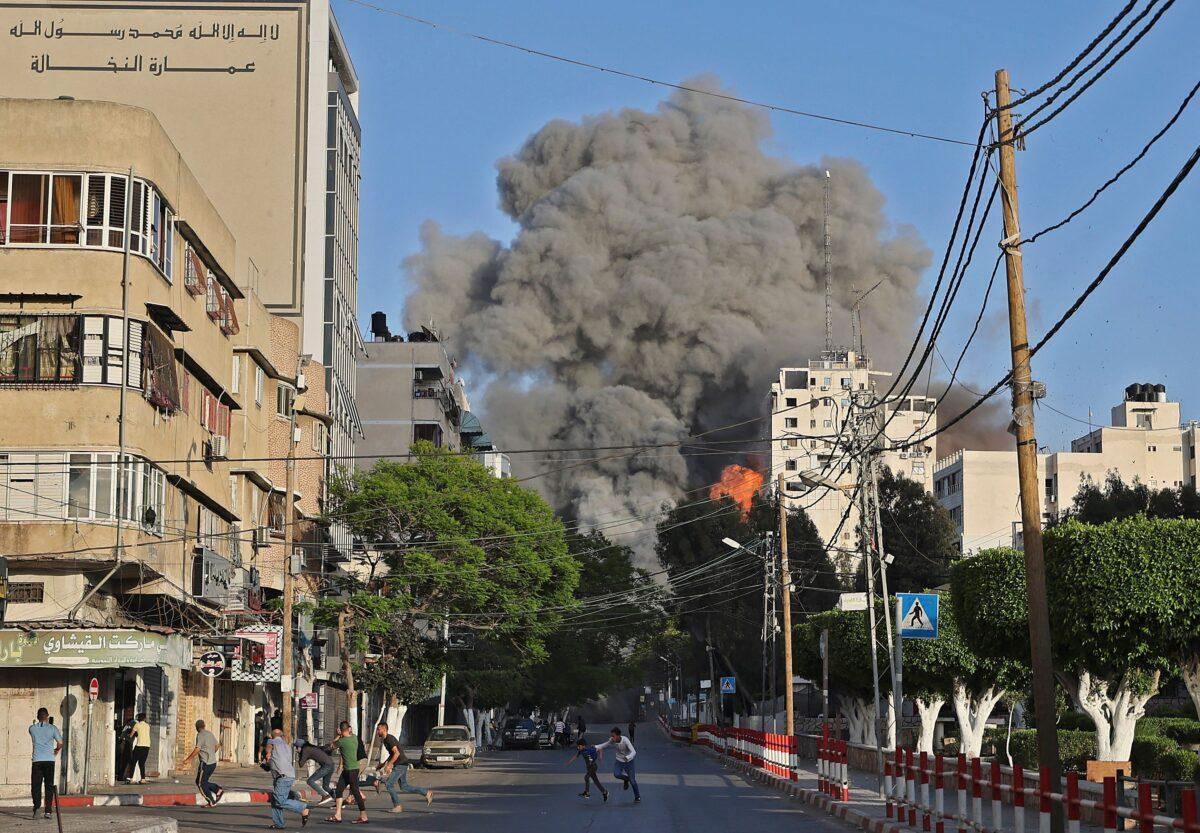 People run away from the vicinity of Al-Sharouk tower as it collapses on May 12 in Gaza City. (Mohammed Abed/AFP via Getty Images)