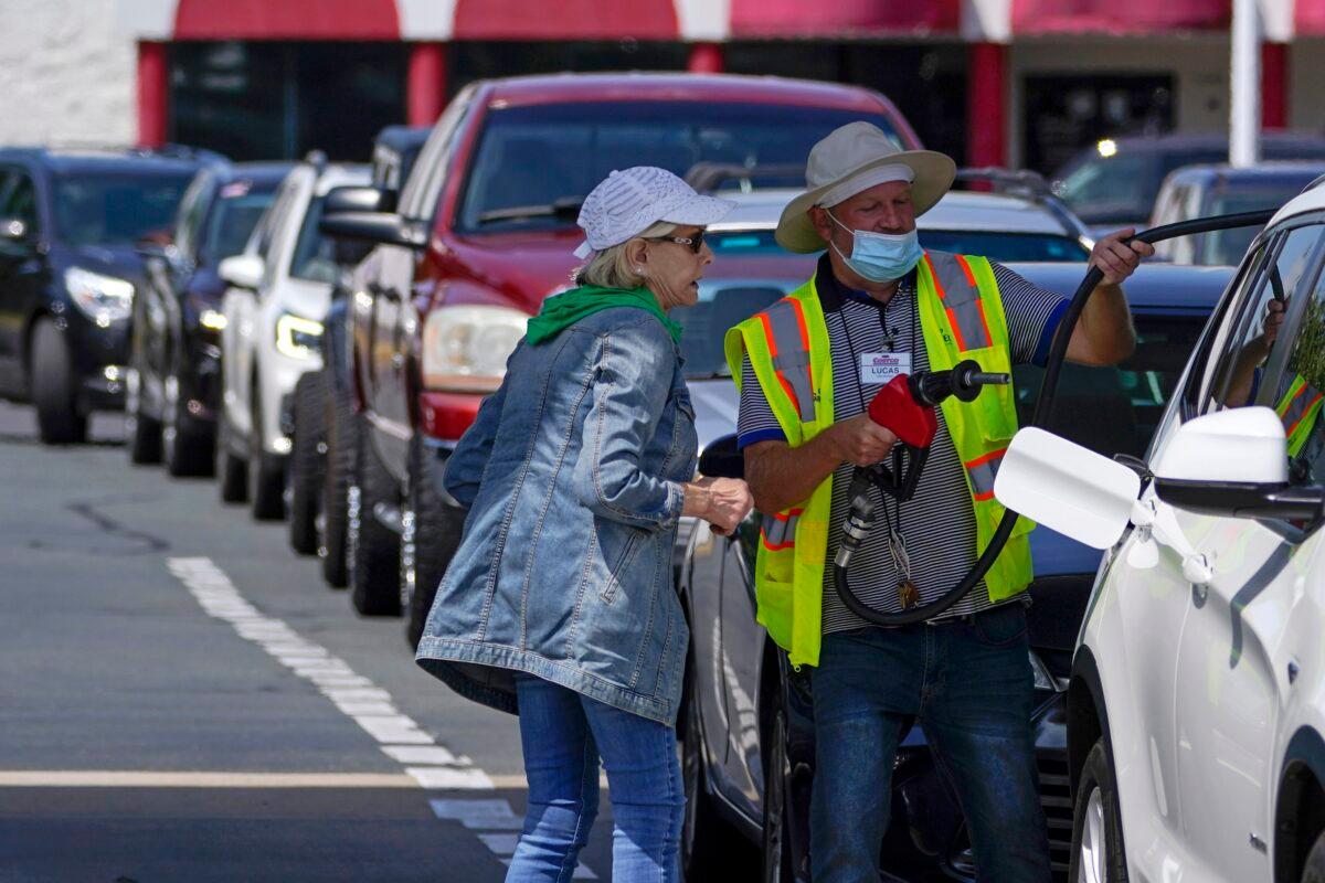 A worker helps a customer pump gas, with long lines stretching behind them, in Charlotte, N.C., on May 11, 2021. (Chris Carlson/AP Photo)