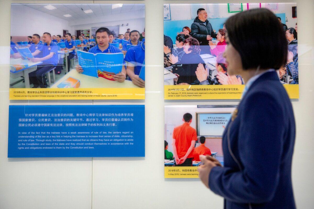 A tour guide stands near a display showing images of people at locations described as vocational training centers in southern Xinjiang at the Exhibition of the Fight Against Terrorism and Extremism in Urumqi in western China's Xinjiang Uyghur Autonomous Region, on April 21, 2021. (Mark Schiefelbein/AP Photo)