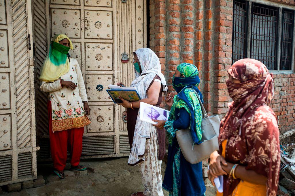 In this picture taken on June 9, 2020, accredited social health activist (ASHA) workers talk to a woman during a door-to-door survey to check on residents after the government eased a nationwide lockdown imposed as a preventive measure against the COVID-19 coronavirus, in Bahadarpur village in Meerut district. - (XAVIER GALIANA/AFP via Getty Images)