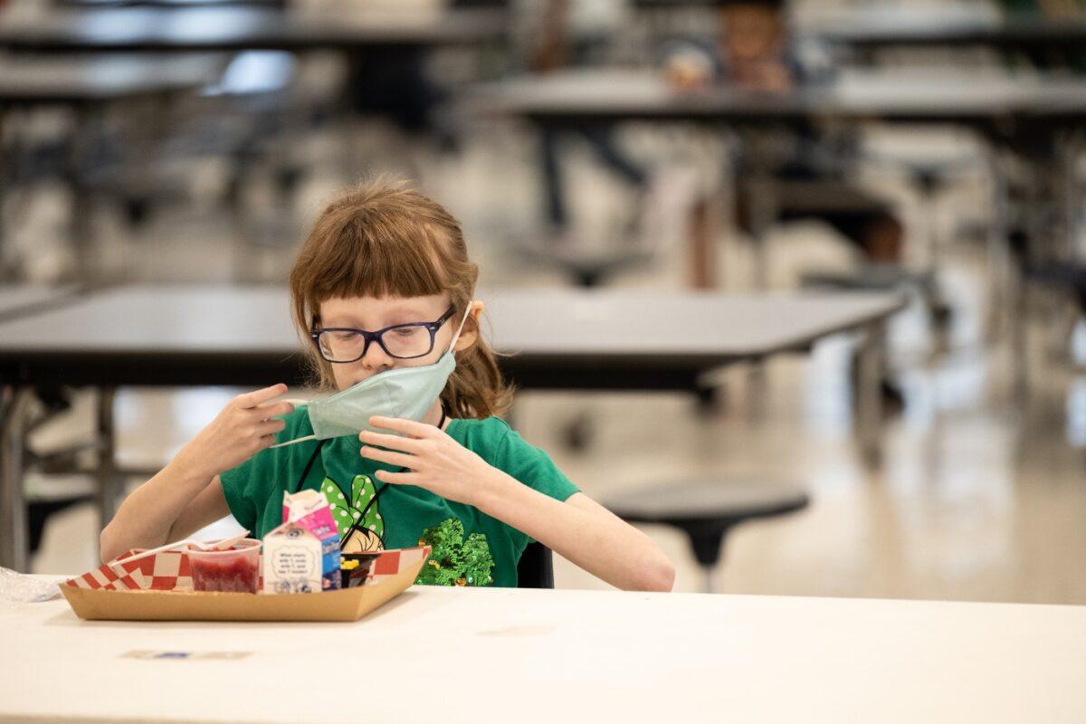 A child puts her mask back on after finishing lunch at a socially distanced table in the cafeteria of Medora Elementary School in Louisville, Ky., on March 17, 2021. (Jon Cherry/Getty Images)