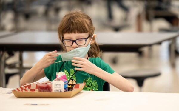 A child puts her mask back on after finishing lunch at a socially distanced table in the cafeteria of Medora Elementary School in Louisville, Ky., on March 17, 2021. (Jon Cherry/Getty Images)