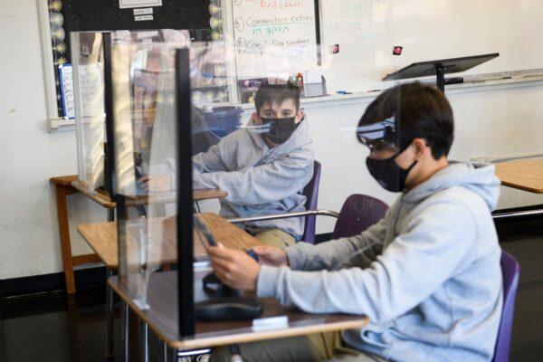Students sit behind barriers and use tablets during an in-person English class at St. Anthony Catholic High School during the COVID-19 pandemic in Long Beach, Calif., on March 24, 2021. (Patrick T. Fallon/AFP via Getty Images)