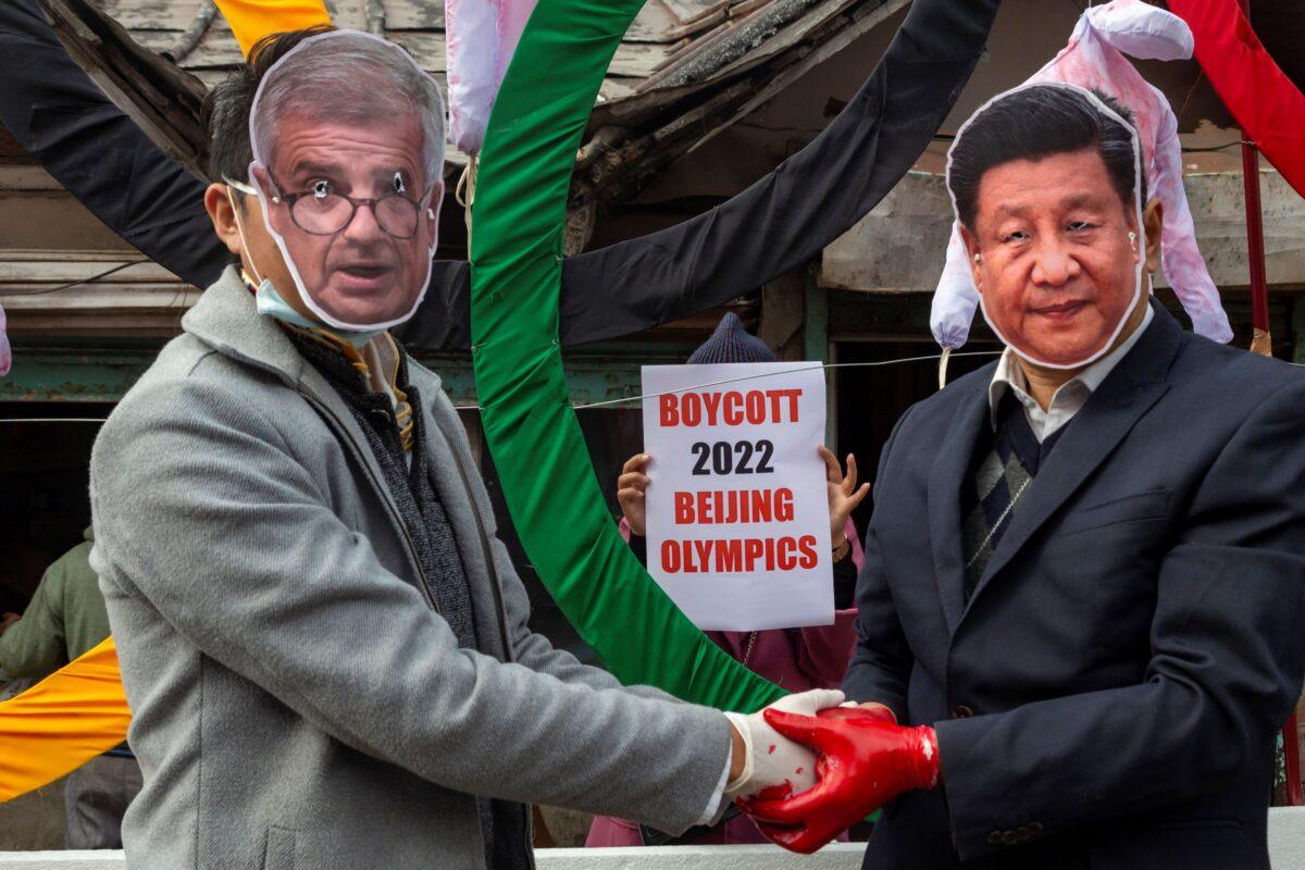 Activists wearing masks of IOC President Thomas Bach (L) and Chinese President Xi Jinping pose in front of the Olympic Rings during a street protest against the holding of the 2022 Beijing Winter Olympics, in Dharmsala, India, on Feb. 3, 2021. (Ashwini Bhatia/AP Photo)