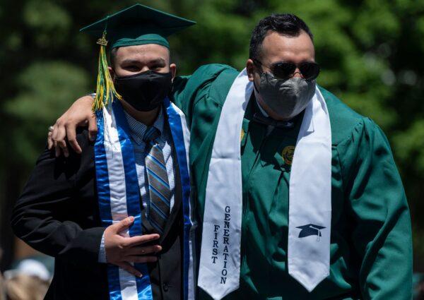 A graduate (R) hugs his brother during a socially distanced graduation ceremony at George Mason University in Fairfax, Va., on May 13, 2021. (ANDREW CABALLERO-REYNOLDS/AFP via Getty Images)