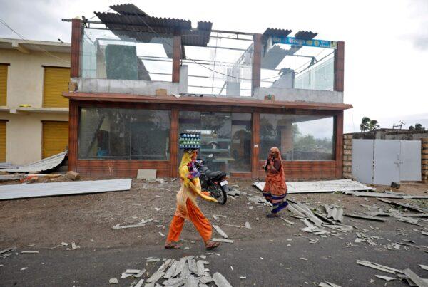 A woman carrying eggs walks past a damaged commercial building after Cyclone Tauktae hit, in Kodinar, in the western state of Gujarat, India, on May 18, 2021. (Amit Dave/Reuters)