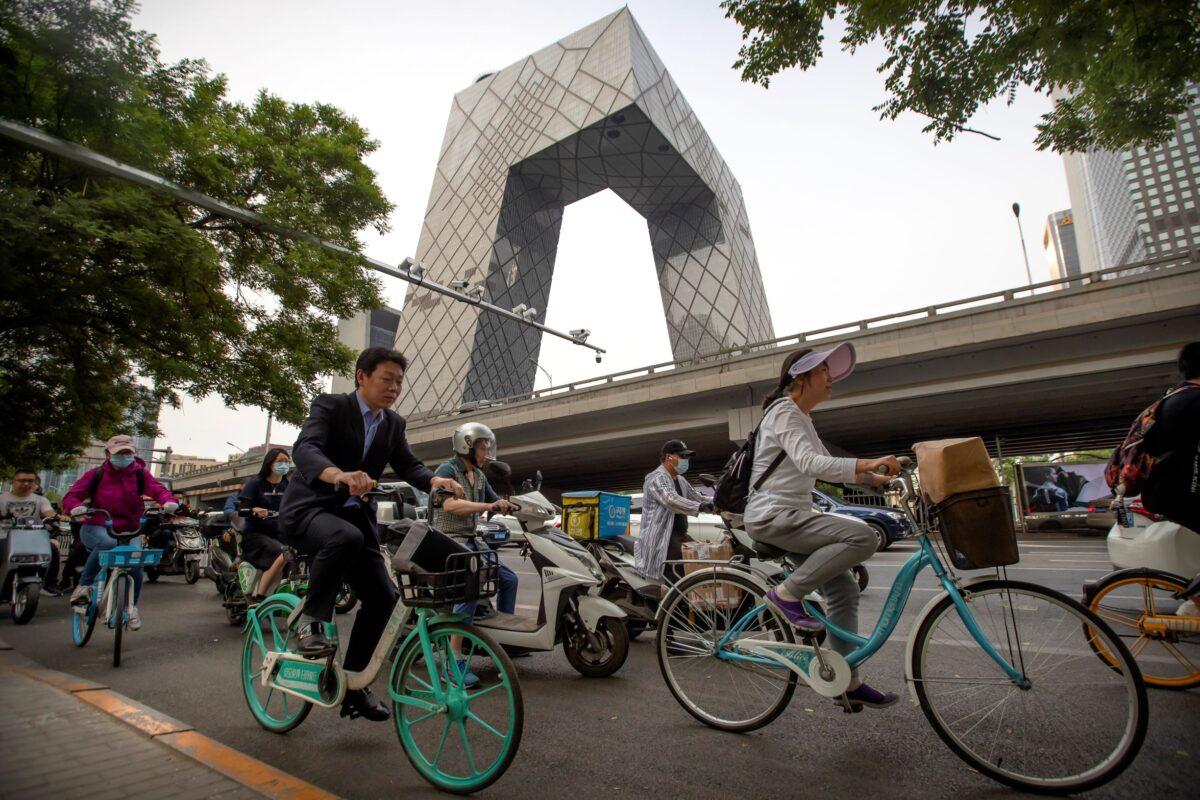 People ride bicycles past the China Central Television (CCTV) headquarters building in Beijing, on May 19, 2021. (Mark Schiefelbein/AP Photo)