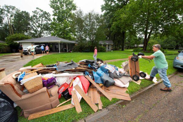 Homeowner Stephen Punkay (R) dumps a cart-load of wet carpet to add to the debris pile, after his home got at least six inches of water in Baton Rouge, La., on May 18, 2021. (Travis Spradling/The Advocate via AP)