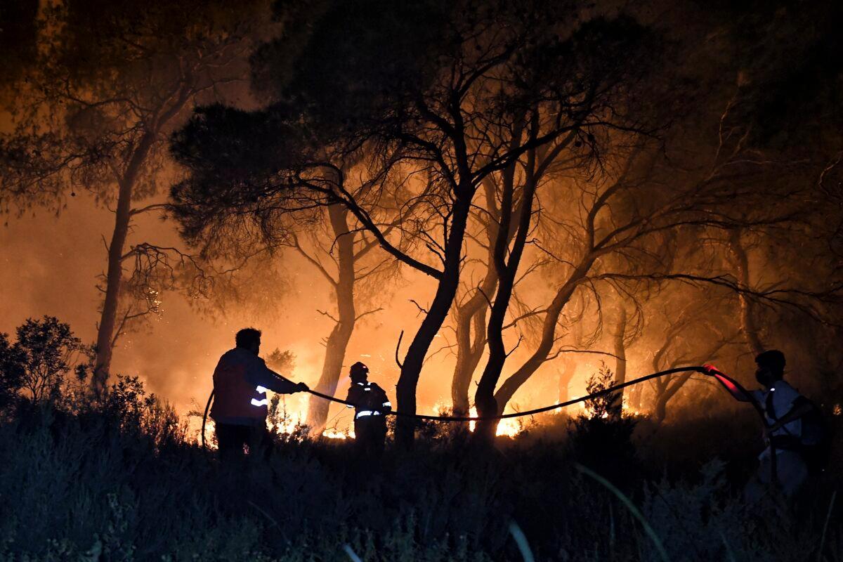 Firefighters try to extinguish the blazes during a wildfire near the village of Schinos, near Corinth, Greece, on May 19, 2021. (Valerie Gache/AP Photo)