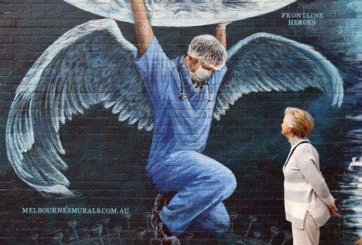 A woman looks at a mural of a health worker with wings holding a globe on International Nurses Day in Melbourne on May 12, 2020. (William West/AFP via Getty Images)
