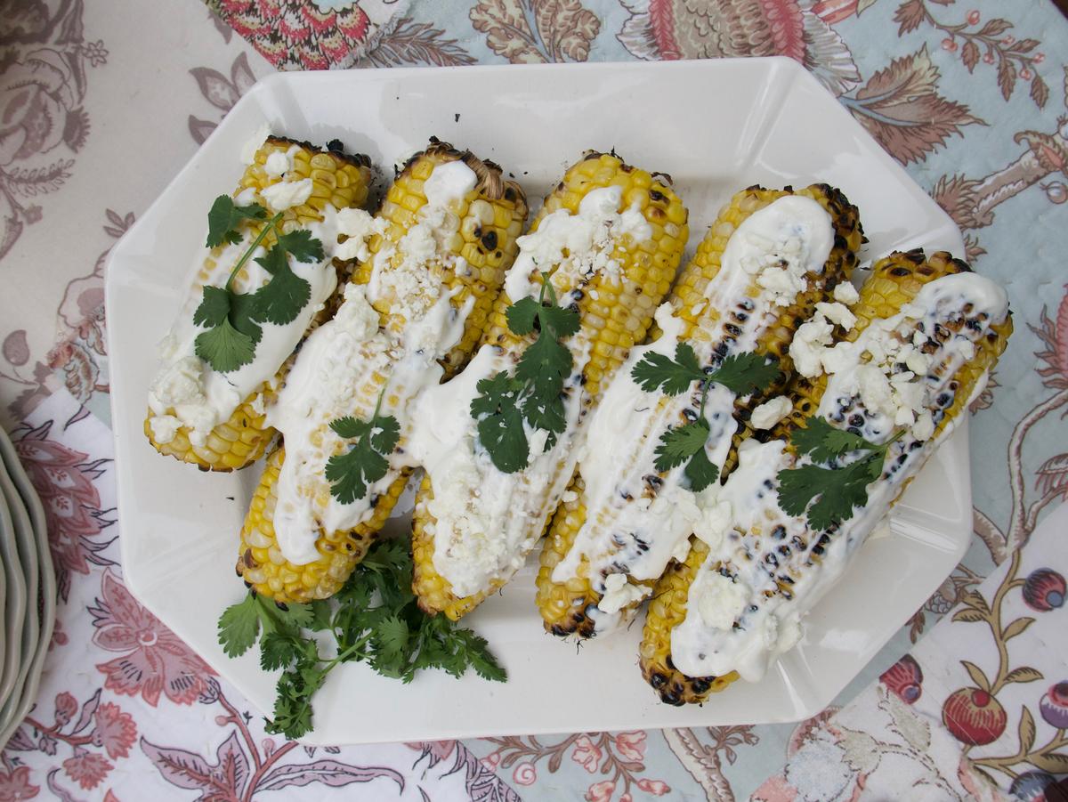A creamy sauce, cotija cheese, and cilantro dress up this Mexican-inspired grilled corn. (Victoria de la Maza)