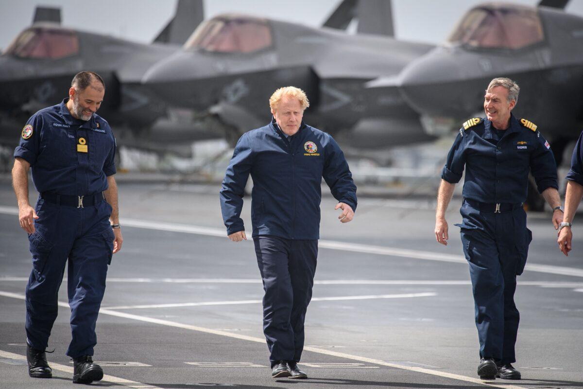 British Prime Minister Boris Johnson walks on the flight deck during a visit to HMS Queen Elizabeth aircraft carrier in Portsmouth, southwest England, prior to its departure for Asia in its first operational deployment, on May 21, 2021. (Leon Neal/POOL/AFP via Getty Images)