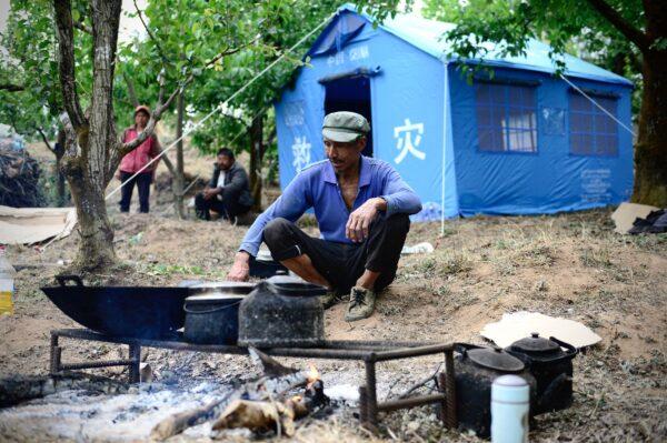 A man cooks in front of tents set up for people displaced by an overnight earthquake in Yangbi County of Dali Prefecture, in southwestern China's Yunnan Province on May 22, 2021. (AFP via Getty Images)