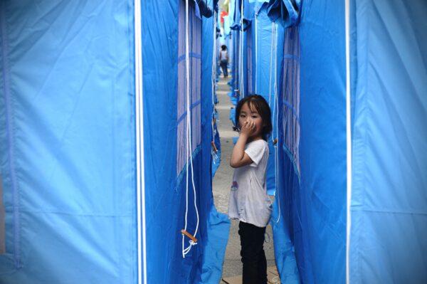 A girl looks out from between tents set up for people displaced by an overnight earthquake in Yangbi County of Dali Prefecture, in China's southwest Yunnan province on May 22, 2021. (AFP via Getty Images)