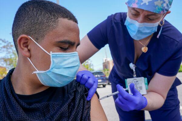 A 13-year-old watches a nurse injects him with a Pfizer COVID-19 vaccine in Freeport, N.Y., on May 14, 2021. (Mary Altaffer/AP Photo)