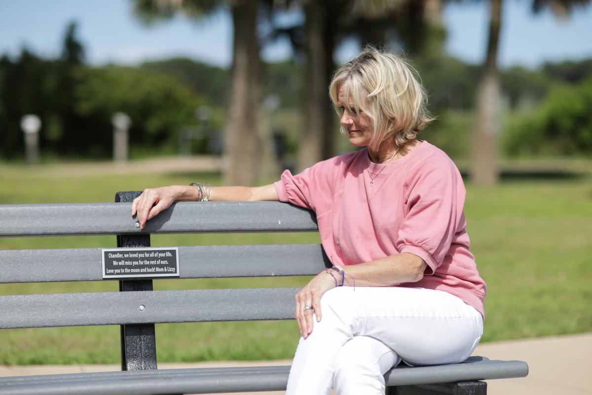  Michele Holbrook sits on a bench in memory of her son, Chandler Cook, at a local park in Fernandina Beach, Fla., on May 19, 2021. The bench was bought by her friends and put up by the city. (Samira Bouaou/The Epoch Times)