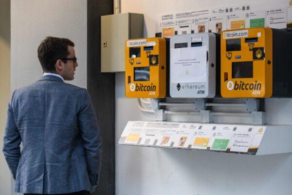 A man looks at ATM machines (L and R) for digital currency Bitcoin in Hong Kong on Dec. 18, 2017. (ANTHONY WALLACE/AFP via Getty Images)