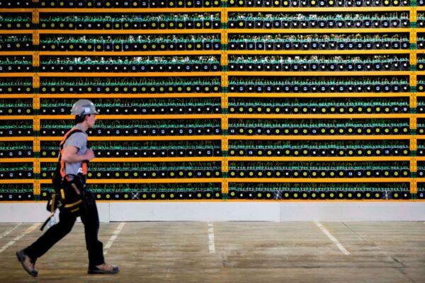 A construction worker walks past bitcoin mining at Bitfarms in Saint Hyacinthe, Quebec, on March 19, 2018. (LARS HAGBERG/AFP via Getty Images)