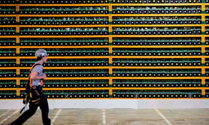 A construction worker walks past bitcoin mining at Bitfarms in Saint-Hyacinthe, Quebec, on March 19, 2018. (Lars Hagberg / AFP via Getty Images)
