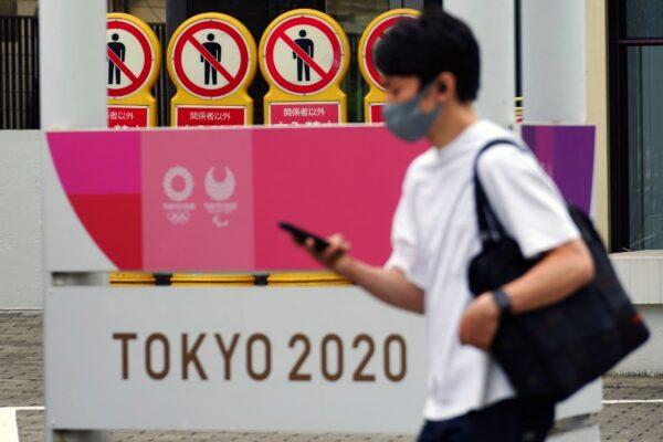 A man walks past a banner for the Tokyo 2020 Olympic and Paralympic Games in Tokyo on May 11, 2021. (Eugene Hoshiko/AP Photo)
