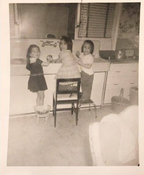 The author (center) and her sisters in their family kitchen, in the 1950s. (Courtesy of Valerie A. Winters)