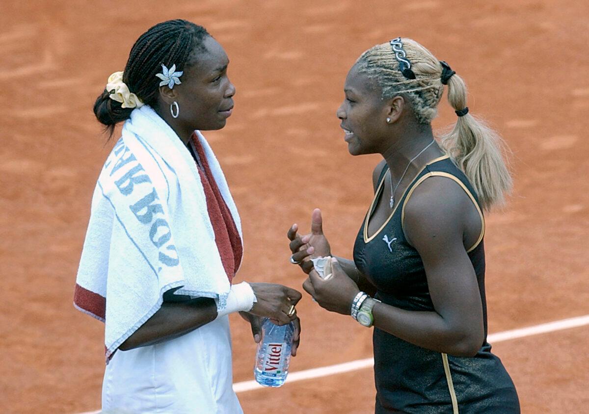 Serena Williams (R) talks with her sister Venus at Roland Garros stadium in Paris, France, on June 8, 2002. (Christophe Ena/AP Photo)