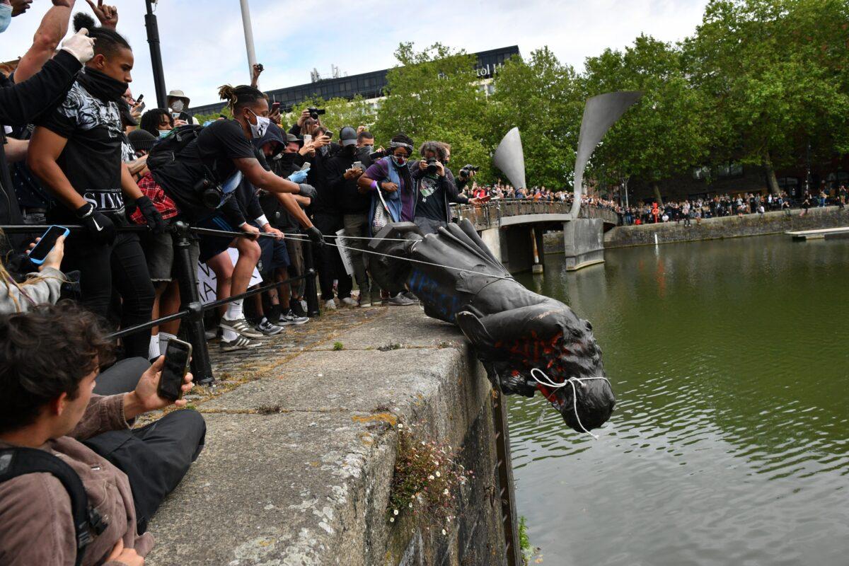 Protesters throwing the statue of Edward Colston into Bristol harbour during a Black Lives Matter protest rally in Bristol, England, on June 7, 2020. (Ben Birchall/PA Media)