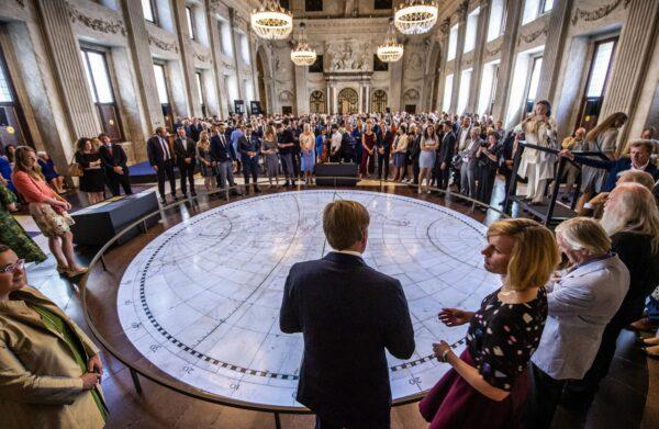 Inlaid with brass on the marble floor, this centrally positioned map outlines the earth's landmasses. When not in official use, the Royal Palace is open to the public. King Willem-Alexander (C) attends the opening of the exhibition "Universe of Amsterdam, Treasures From the Golden Age of Cartography" on June 28, 2019. (FRANK VAN BEEK/AFP via Getty Images)