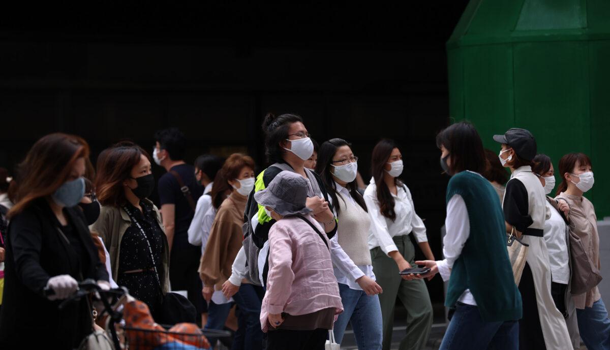 Pedestrians wear protective face masks as they cross the road at Umeda commercial and entertainment district in Osaka, Japan, on May 28, 2021. (Buddhika Weerasinghe/Getty Images)