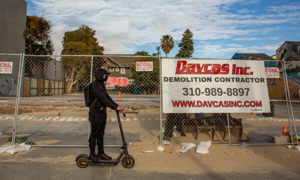 A man on an electric scooter drives past the site of a building that was torched by homeless individuals, in Venice Beach, Calif., on Jan. 27, 2021. (John Fredricks/The Epoch Times)