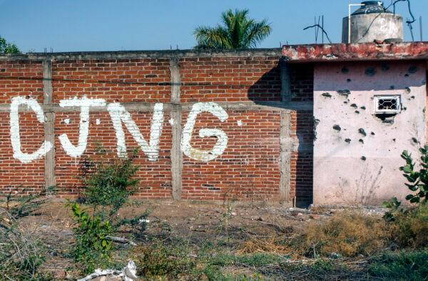 View of a bullet-riddled wall bearing the initials of the criminal group Cartel Jalisco Nueva Generacion (CJNG) at the entrance of the community of Aguililla, state of Michoacan, Mexico, on April 23, 2021. (Enrique Castro/AFP via Getty Images)