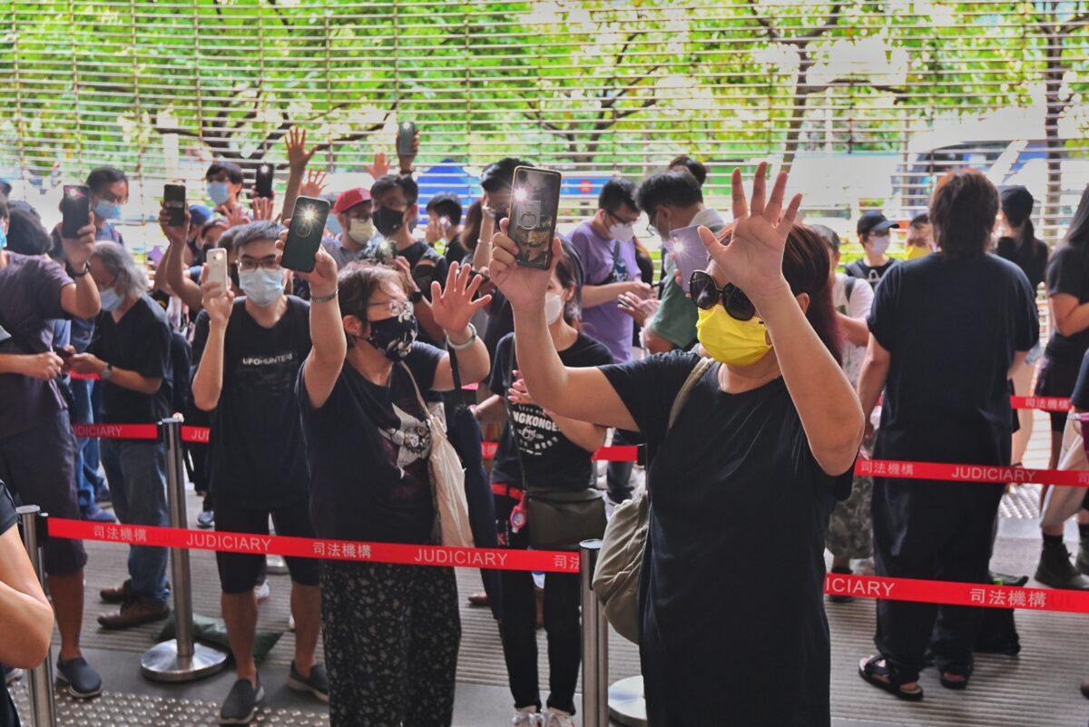People hold up five fingers to support the 47 pro-democracy opposition figures outside of the West Kowloon court building in Hong Kong on May 31, 2021. (Sung Pi-lung/The Epoch Times)