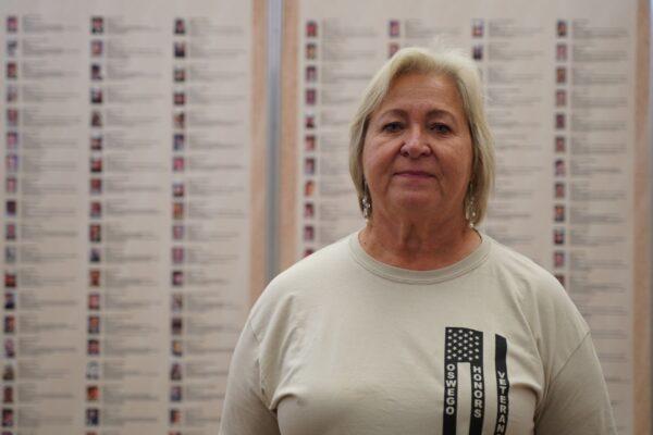 Pat Mastenbrook in front of the Wall of Honor at Oswego Township Hall, in Oswego, Ill. (Cara Ding/The Epoch Times)