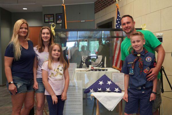 The Barczak family in front of a display honoring soldiers missing in action at Oswego Township Hall, in Oswego, Ill. (Cara Ding/The Epoch Times)