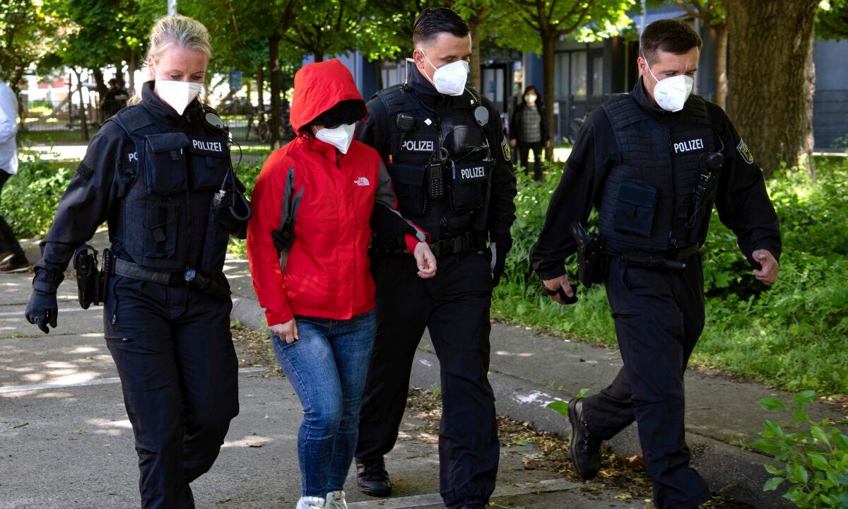 Police officers lead a woman to a vehicle during a raid against a group of people suspect to brought Vietnamese people to Europe on fraudulently obtained visas, in Berlin, on May 31, 2021. (Paul Zinken/dpa via AP)