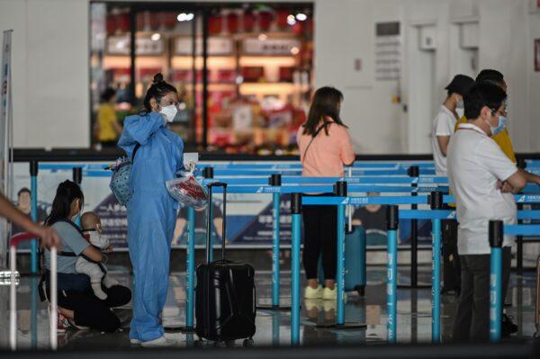 A passenger wearing a protective gear and a face mask waits in line at an airline counter at Tianhe airport in Wuhan, in China's central Hubei province on May 23, 2020. (Hector Retamal/AFP via Getty Images)