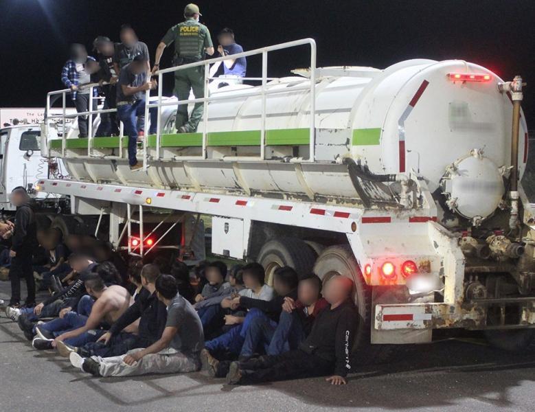 Illegal aliens sit beside a tanker-trailer after being discovered and apprehended by Border Patrol agents, in a file photo. (CBP)