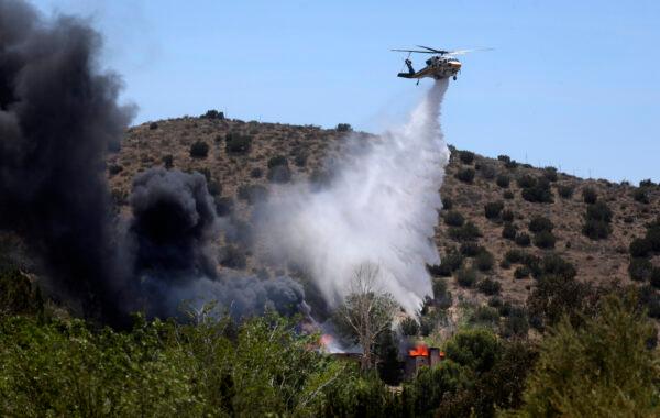 A firefighting helicopter makes a water drop on a house engulfed in fire, in Acton, Calif., on June 1, 2021, where a suspect fled to after a shooting at a fire station. (David Swanson/AP Photo)