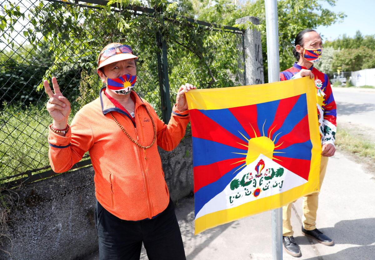 Activists hold a Tibetan flag next to a street sign in a street renamed 'Martyrs of Uyghur,' near the planned site of the Chinese Fudan University campus, in Budapest, Hungary, on June 2, 2021. (Bernadett Szabo/Reuters)