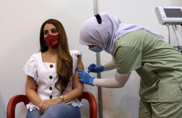 A young woman receives a COVID-19 vaccine at the Bahrain International Exhibition and Convention Center in the capital Manama. Bahrain has approved both the Pfizer/BioNTech vaccine and another developed by Chinese firm Sinopharm. Dec. 24, 2020. (Mazen Mahdi/AFP via Getty Images)