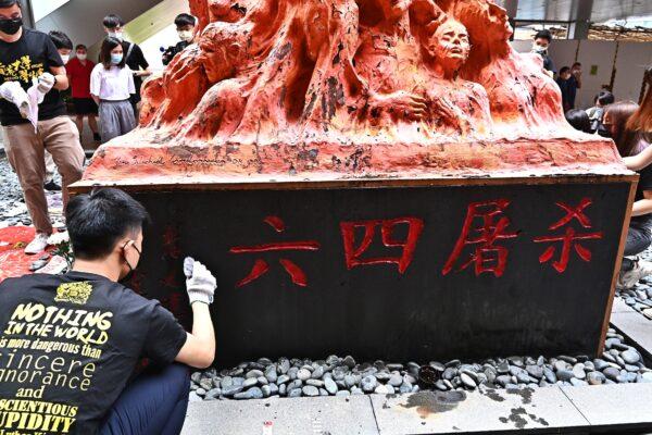 A student before the Pillar of Shame in Hong Kong, with the statue’s base showing the words “June 4th Massacre.” (Sung Pi-lung/The Epoch Times)